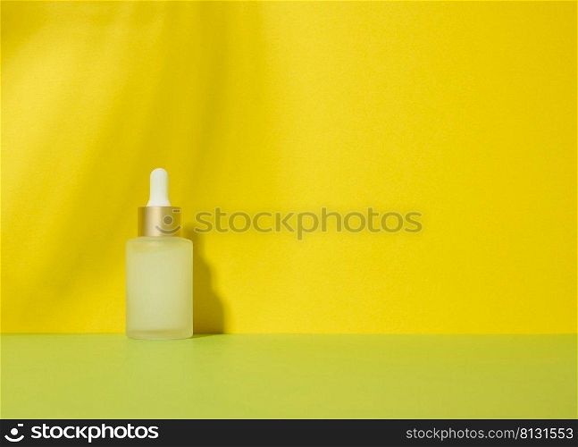 White glass transparent bott≤with aπpette for cosmetics, oils, acids. Yellow background