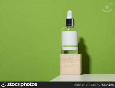white glass vial with pipette and white blank paper label on green background. Template for liquid cosmetic products tincture, essence, acid