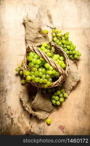 White grapes in a basket. On a wooden table.. White grapes in a basket.