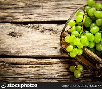 White grapes in a basket. On a wooden table.. White grapes in a basket.