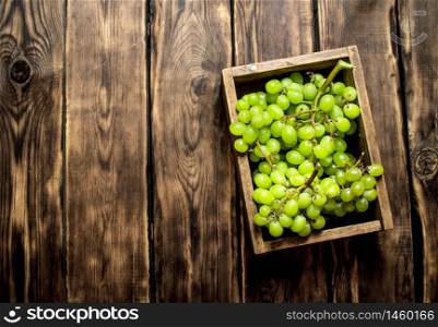 White grapes in an old box. On wooden background.. White grapes in an old box.
