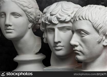 White gypsum copy of ancient statue of Germanicus, Antinous and Venus head for artists on a dark textured background. Plaster sculpture of statue face.. Gypsum copy of ancient statue Germanicus, Antinous and Venus head on dark textured background. Plaster sculpture face.