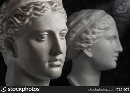White gypsum copy of ancient statue of Venus and Diana head for artists on a dark textured background. Plaster sculpture of statue face.. Gypsum copy of ancient statue Venus and Diana head on dark textured background. Plaster sculpture face.