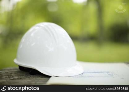 White hard hat on building plans outdoors