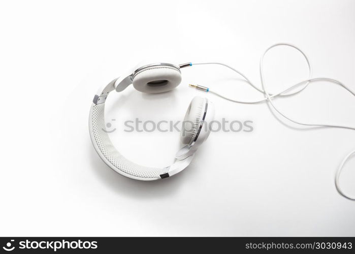 White headphones and Convention Aux cable 3.5 mm. Isolated on white background. White headphones and Convention Aux cable 3.5 mm