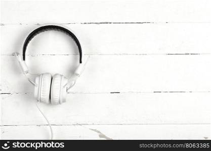 White headphones with wire on white background wooden. White headphones with wire on white background
