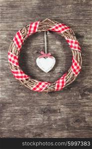 White heart and wreath over wooden old background. The wooden heart