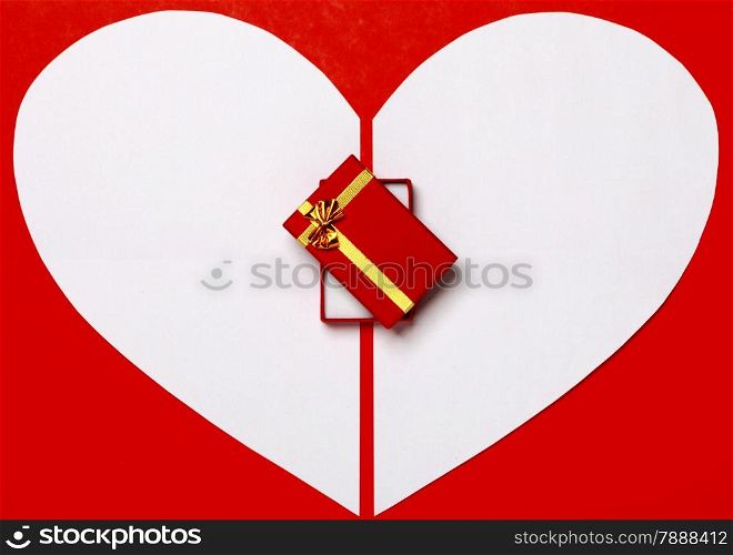 White heart paper on red background and gift box with gold ribbon. Valentine&rsquo;s Day or holiday greeting card. Heart symbol frame.