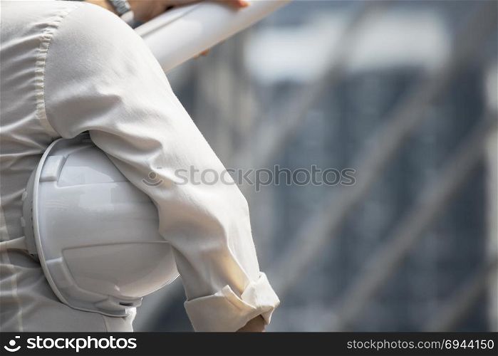 White helmet of engineer architect holding by businessman as background, back view