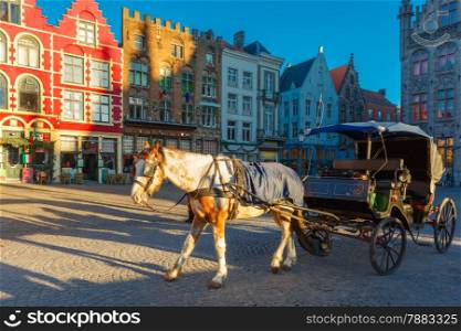 White horse hitched to a four wheel horse carriage waiting for tourists on Grote Markt square of Brugge Christmas, Belgium.