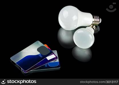 white innovation energy-saving LED bulb and credit cards on black background