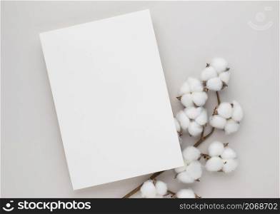 White invitation card mockup with a cotton flower on beige background, Minimal beige workplace composition, flat lay, mockup