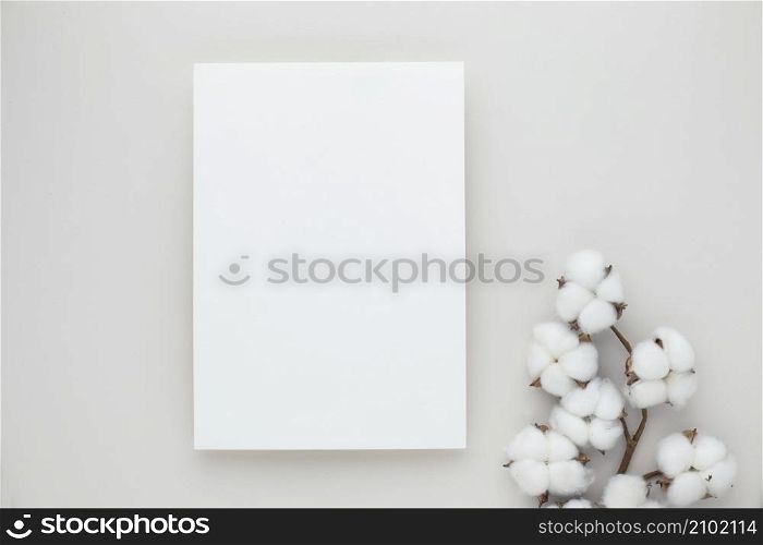 White invitation card mockup with a cotton flower on beige background, Minimal beige workplace composition, flat lay, mockup