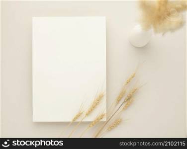 White invitation card mockup with a dried grass and ceramic vase on beige background, Minimal beige workplace composition, flat lay, mockup