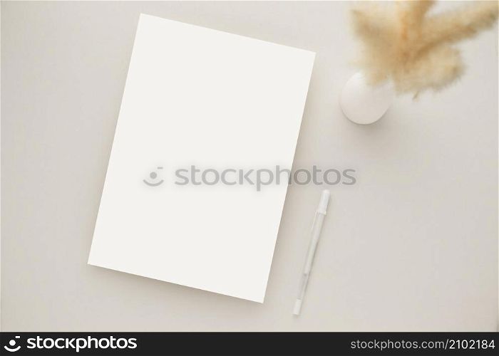 White invitation card mockup with a dried grass and ceramic vase on beige background, Minimal beige workplace composition, flat lay, mockup