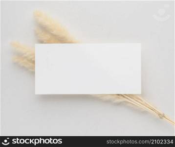 White invitation card mockup with a dried grass on beige background, Minimal beige workplace composition, flat lay, mockup