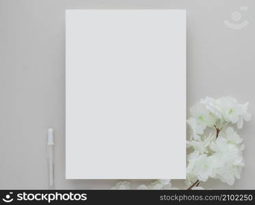 White invitation card mockup with a white flower on beige background, Minimal beige workplace composition, flat lay, mockup