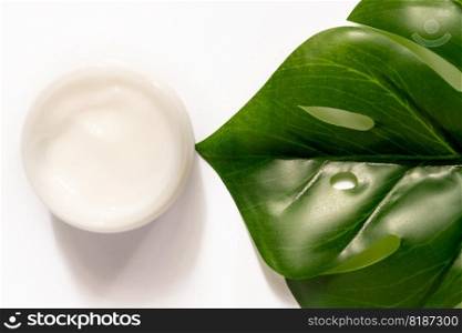 White jar of face cream on a background of monstera or Swiss cheese plant. white background, top view, flat lay. Concept natural cosmetics. White jar of face cream on a background of monstera or Swiss cheese plant. white background, top view, flat lay. Concept natural cosmetics.