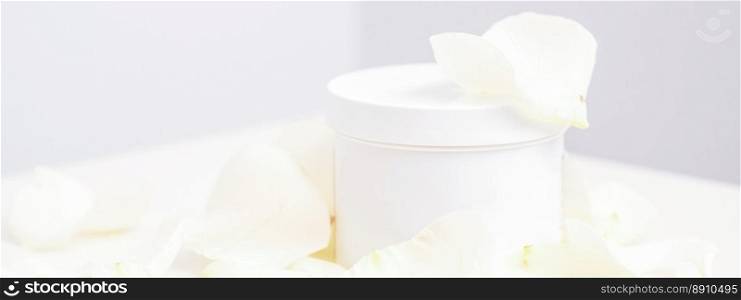 White jar with cream among delicate white rose flowers petals on a light background. Natural organic cosmetics concept, close up, mock-up. White jar with cream among delicate white rose flowers petals on a light background. Natural organic cosmetics concept, close up, mock-up.