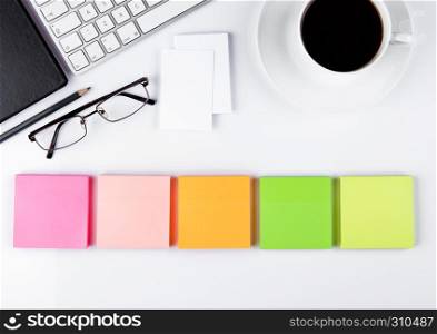 White keyboard with glasses and sticky note paperson white background