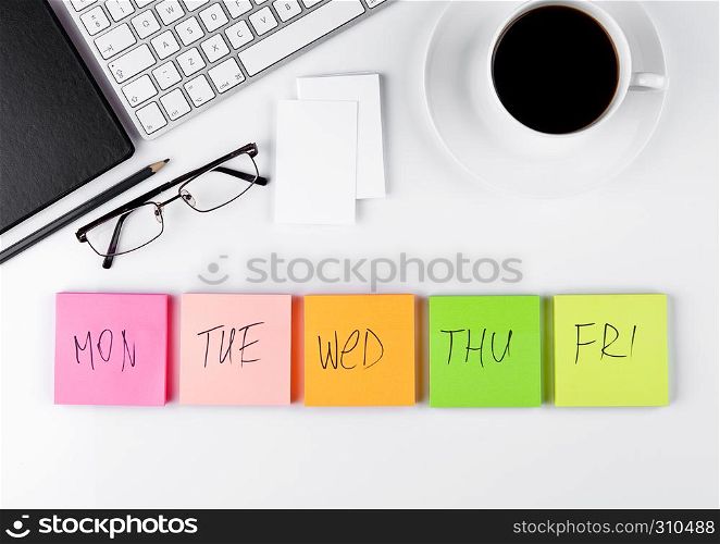 White keyboard with glasses and sticky note paperson white background