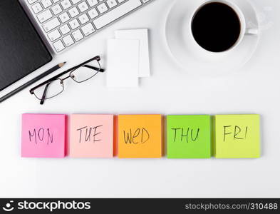 White keyboard with glasses and sticky note paperson white background