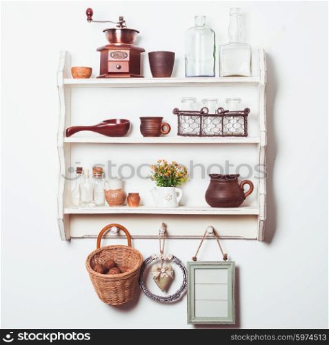White kitchen shelves in rustic style with kitchenware on the white wall. Shelves in rustic style
