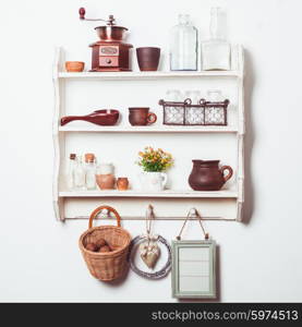 White kitchen shelves in rustic style with kitchenware on the white wall. Shelves in rustic style