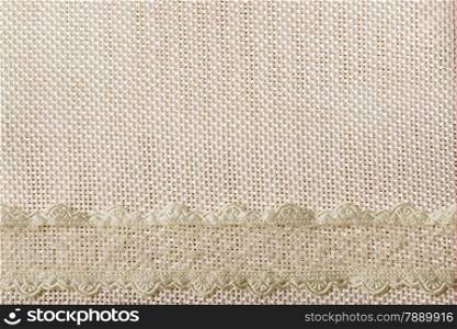 White lace ribbon frame on light material, sack cloth background