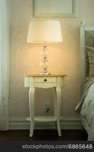 white lamp on bedside wooden table in luxury bedroom