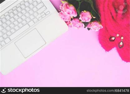 White laptop computer with woman accessories and pink roses on pink background, Lifestyle concept with copy space