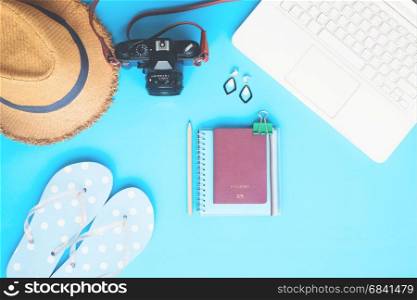 White laptop computer with woman accessories, camera and passport on blue color background, Summer travel concept