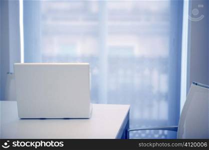 White laptop open on a white room, blue light