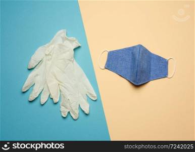 white latex gloves and blue reusable textile mask on a blue beige background, hygiene and virus protection accessories for epidemics and pandemics, overhead view