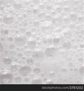 White liquid soap foam with air bubbles background texture closeup. Square format