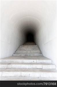 White marble staircase leading to dark tunnel