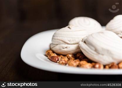 white marshmallows and sweet peanuts on the plate and wood