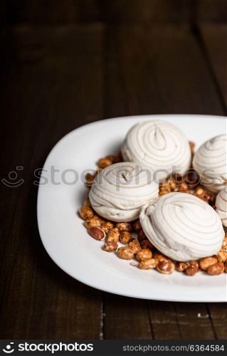 white marshmallows and sweet peanuts on the plate and wood