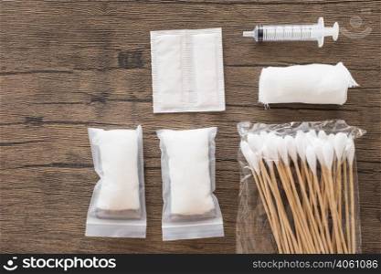 white medical cotton gauze bandage syringe pack cotton swab wooden table