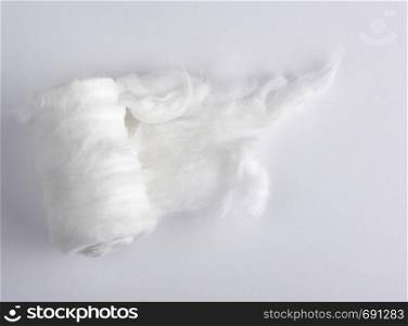 white medical cotton twisted into a roll on a white background, top view