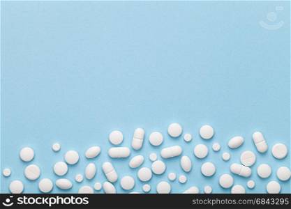 White medical pills on blue background. Copy space. Top view