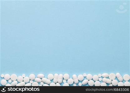 White medical pills on blue background. Copy space. Top view