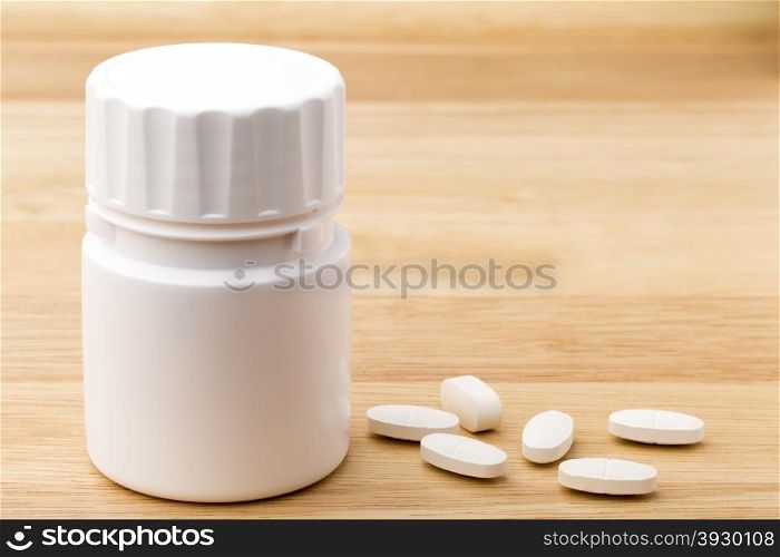 White medicine pills bottle on wooden table background. White pills bottle on wooden table background