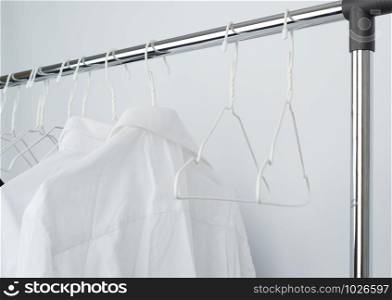white men&rsquo;s crumpled shirts hanging on a metal hanger, white background