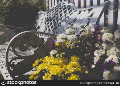 white metal chair and bouquet of blooming flower on lawn yard in park