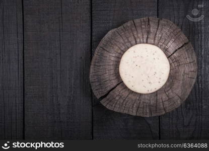 white milk cheese with seeds on a wooden end of a tree