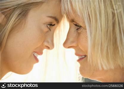 White mother and daughter face to face looking at each other.