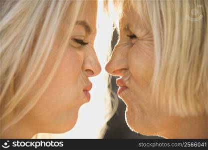 White mother and daughter face to face squinting at each other.