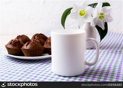 White mug mockup with chocolate muffins on plate. Empty mug mock up for design presentation. . White mug mockup with chocolate muffins on plate