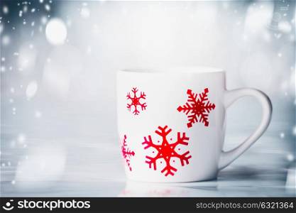 White mug with red snowflakes on blue snowfall background, front view. Happy winter holiday card layout